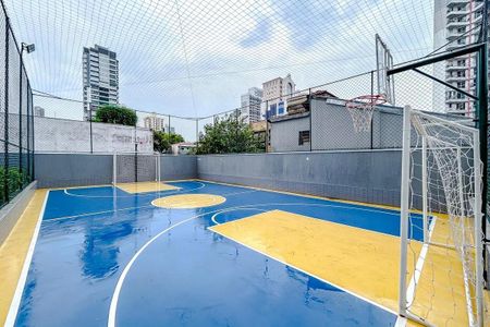 Apartamento à venda com 63m², 2 quartos e 1 vaga Apartamento à venda com 63m², 2 quartos e 1 vagaQuadra de futsal com piso azul e amarelo, cercada por muro e rede, com balneário e churrasqueira ao fundo.
