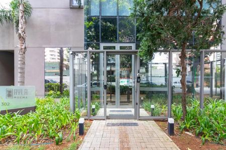 Apartamento à venda com 170m², 6 quartos e 2 vagas Apartamento à venda com 170m², 6 quartos e 2 vagasEntrada de um edifício com jardim e árvore, com vista para a rua e outros edifícios.
