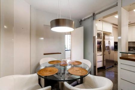 Tabela redonda com vidro e seis cadeiras brancas, iluminada por uma lâmpada circular. de apartamento à venda com 4 quartos, 256m² em Planalto Paulista, São Paulo