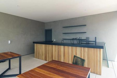 Studio à venda com 33m², 1 quarto e sem vaga Studio à venda com 33m², 1 quarto e sem vagaBarra de madeira e pedra negra, com mesas de madeira e bancos de metal, em ambiente com iluminação natural e paredes de concreto.