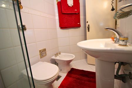 Banheiro com piso de porcelanato, vaso sanitário e pia de porcelanato, com uma toalha vermelha pendurada na parede. de apartamento para alugar com 2 quartos, 108m² em Leblon, Rio de Janeiro