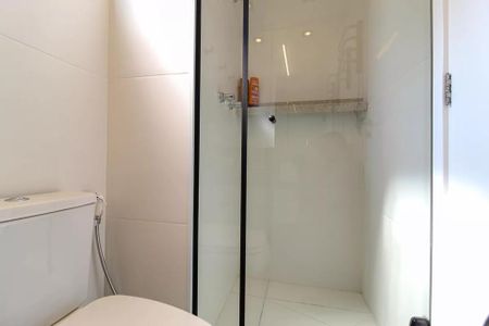 Banheiro com chuveiro e vaso sanitário branco, com uma parede de azulejos brancos e um espelho acima do vaso sanitário. de kitnet/studio à venda com 1 quarto, 21m² em Indianópolis, São Paulo