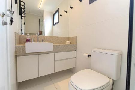 Banheiro com pia e vaso sanitário brancos, armário de madeira e espelho grande. de kitnet/studio à venda com 1 quarto, 21m² em Indianópolis, São Paulo