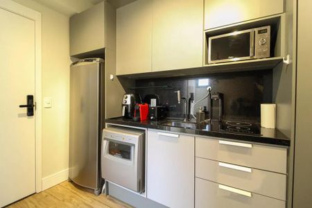 Studio à venda com 21m², 1 quarto e sem vaga Studio à venda com 21m², 1 quarto e sem vagaCozinha com geladeira, fogão e microondas, com móveis em tons de cinza e preto.