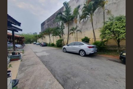 Casa à venda com 66m², 2 quartos e 1 vagaPátio com vários carros e uma parede com palmeiras e arbustos.