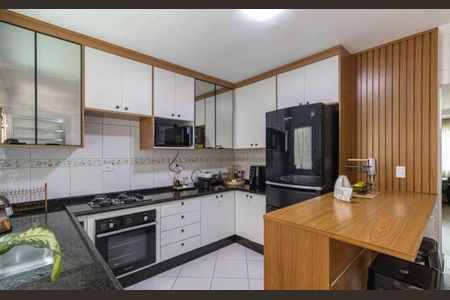 Casa à venda com 180m², 3 quartos e 2 vagasCozinha com móveis brancos e madeira, piso de porcelanato, eletrodomésticos modernos e iluminação adequada.
