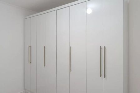 Apartamento à venda com 50m², 1 quarto e 1 vagaCabinets de armário brancos com portas de vidro e manivelas de metal, em uma sala branca e iluminada.