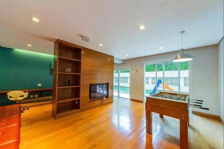 Sala de jogos com mesa de futebol, TV e móveis de madeira, com vista para a piscina e o jardim. de apartamento à venda com 6 quartos, 152m² em Jardins, São Paulo