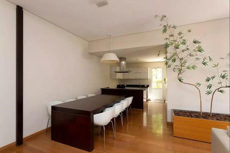 Sala de jantar com mesa de madeira e cadeiras brancas, iluminada por lâmpadas suspensas. de apartamento à venda com 6 quartos, 152m² em Jardins, São Paulo