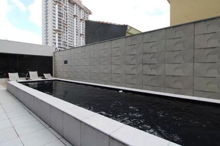 Studio à venda com 23m², 2 quartos e sem vagaPiscina com paredes de pedra e churrasqueira ao fundo, com vista para edifícios altos.