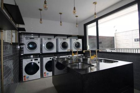 Lavanderia comum com geladeiras e fogões, iluminada por lâmpadas de luz incandescente. de kitnet/studio à venda com 2 quartos, 23m² em Jardim das Acacias, São Paulo