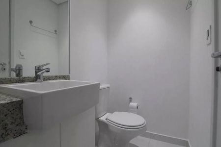 Banheiro com pia e vaso sanitário brancos, espelho e chuveiro, com iluminação adequada e acabamento de gesso. de kitnet/studio à venda com 2 quartos, 23m² em Jardim das Acacias, São Paulo