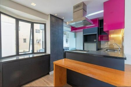 Cozinha moderna com móveis em tons de rosa e preto, iluminada por luzes brancas e com uma bancada de granito. de apartamento à venda com 2 quartos, 50m² em Pinheiros, São Paulo