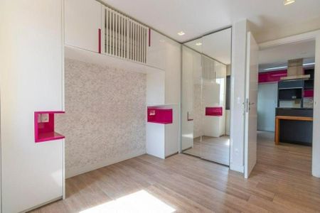 Quarto com cama de casal, armários e móveis brancos e rosa, com iluminação natural e madeira no chão. de apartamento à venda com 2 quartos, 50m² em Pinheiros, São Paulo