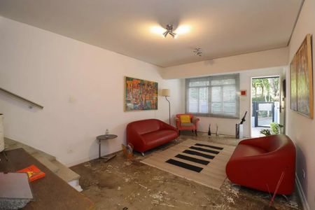 Sala com dois sofás vermelhos, uma mesa redonda e uma pintura na parede. de casa à venda com 2 quartos, 110m² em Perdizes, São Paulo