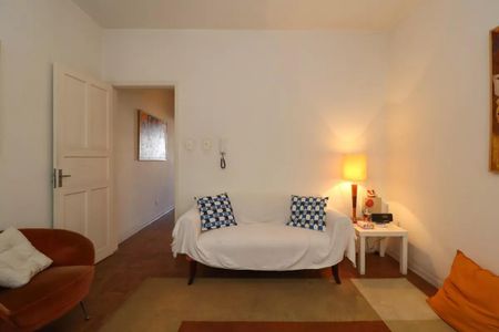 Casa à venda com 110m², 2 quartos e 2 vagasSala com sofá, mesa e porta, com uma decoração simples e minimalista.