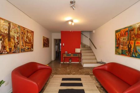 Sala com duas poltronas vermelhas e quadros de arte na parede. de casa à venda com 2 quartos, 110m² em Perdizes, São Paulo