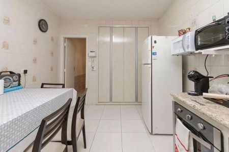 Casa à venda com 220m², 4 quartos e 3 vagas Casa à venda com 220m², 4 quartos e 3 vagasCozinha com geladeira, fogão e mesa com cadeiras, com um relógio na parede e uma porta de acesso a uma área externa.