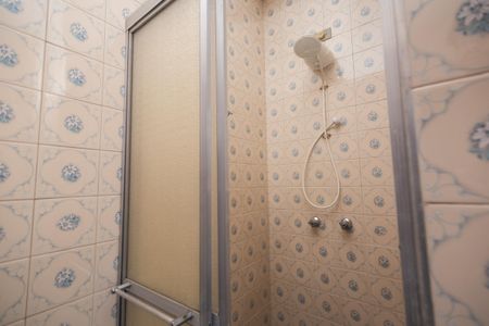 Casa à venda com 250m², 4 quartos e 2 vagas Casa à venda com 250m², 4 quartos e 2 vagasBanheiro com piso de azulejos e chuveiro, com uma porta de vidro e uma janela pequena.