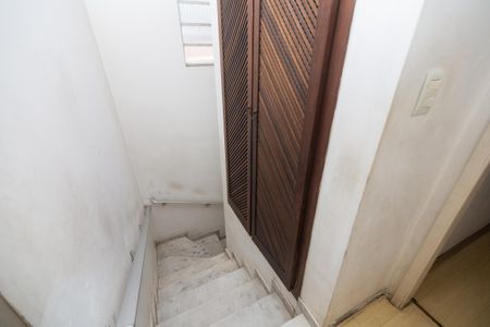 Casa à venda com 250m², 4 quartos e 2 vagas Casa à venda com 250m², 4 quartos e 2 vagasEscada com portas de madeira e paredes brancas, iluminada por uma janela pequena.