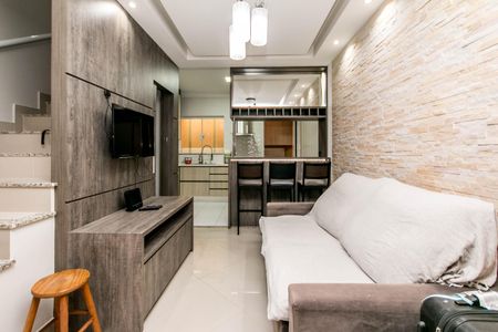 Casa à venda com 74m², 2 quartos e 1 vaga Casa à venda com 74m², 2 quartos e 1 vagaSala de estar com sofá, TV e mesa de madeira, iluminada por lâmpadas de design.
