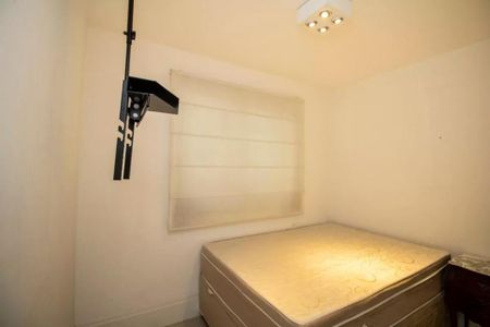 Cama simples com colchão e cortina de vidro, iluminada por lâmpada de teto. de apartamento à venda com 4 quartos, 113m² em Indianópolis, São Paulo