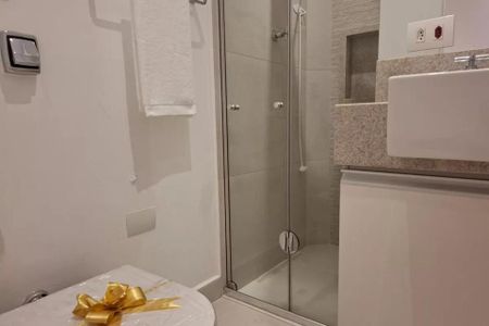 Banheiro com chuveiro e pia, com toalha branca pendurada na parede. de kitnet/studio à venda com 1 quarto, 38m² em Cerqueira César, São Paulo