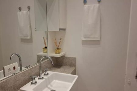 Banheiro com pia e espelho, com duas toalhas penduradas e dois frascos de perfume no espelho. de kitnet/studio à venda com 1 quarto, 38m² em Cerqueira César, São Paulo