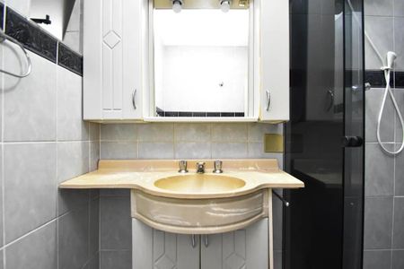 Apartamento à venda com 88m², 2 quartos e sem vagaBanheiro com pia e armário de madeira, com uma porta de vidro e uma janela pequena.