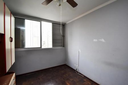 Apartamento à venda com 88m², 2 quartos e sem vagaQuarto com móveis e piso de madeira, com uma janela grande e iluminado por uma lâmpada de teto.