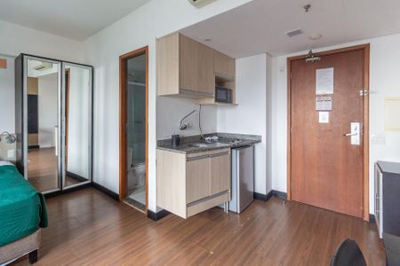 Quarto com cama, armário e porta de vidro, com uma pequena cozinha e banheiro. de kitnet/studio à venda com 1 quarto, 29m² em Bela Vista, São Paulo