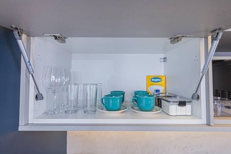 Apartamento à venda com 27m², 1 quarto e 1 vagaCupboard com pratos e copos, talheres e xícaras, e uma caixa de sabão em pó.