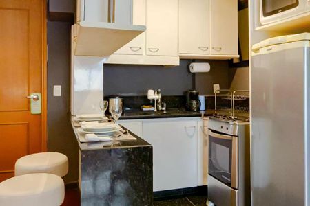 Apartamento para alugar com 110m², 2 quartos e 1 vaga Apartamento para alugar com 110m², 2 quartos e 1 vagaCozinha com móveis brancos e azulejos pretos, com uma mesa de jantar preparada.