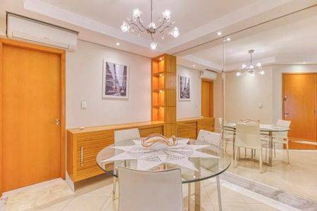 Sala de jantar com mesa de vidro e cadeiras brancas, iluminada por lâmpadas de cristal e com uma decoração simples e elegante. de apartamento à venda com 4 quartos, 115m² em Indianópolis, São Paulo