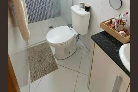 Banheiro com piso de porcelanato, vaso sanitário e lavabo brancos, e uma pequena prateleira de madeira. de casa à venda com 4 quartos, 63m² em Vila Dalila, São Paulo